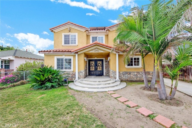 mediterranean / spanish home with stone siding, french doors, and stucco siding