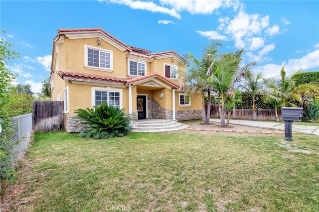 mediterranean / spanish-style home featuring stucco siding, stone siding, a tiled roof, and a fenced backyard