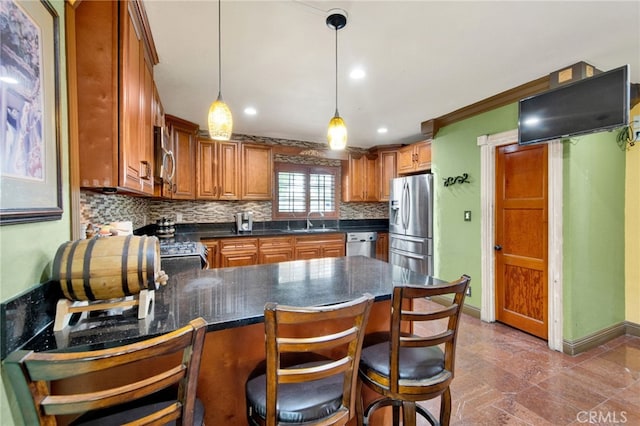 kitchen featuring a sink, baseboards, a peninsula, tasteful backsplash, and appliances with stainless steel finishes