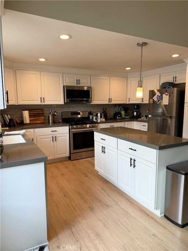 kitchen with dark countertops, white cabinets, light wood-type flooring, and appliances with stainless steel finishes