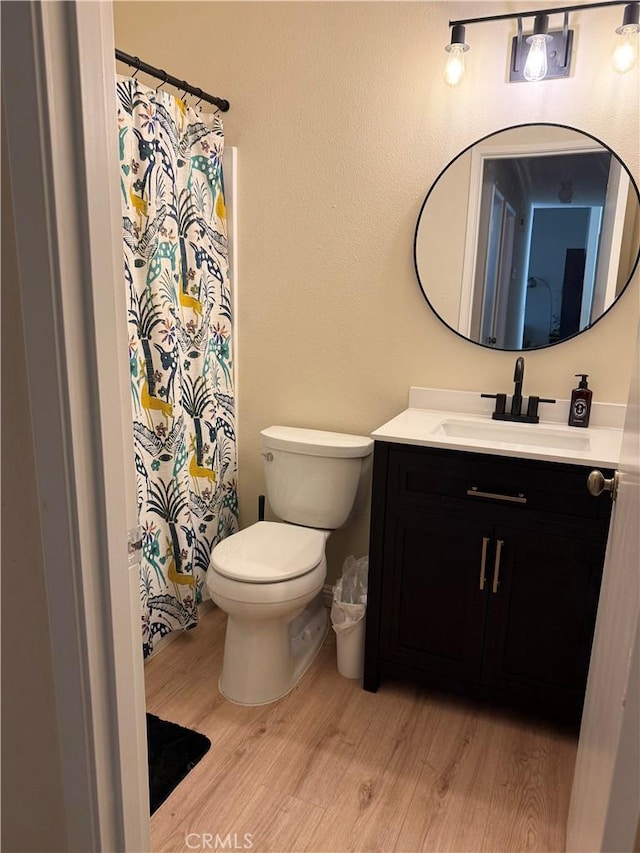 full bathroom with toilet, a shower with shower curtain, wood finished floors, and vanity