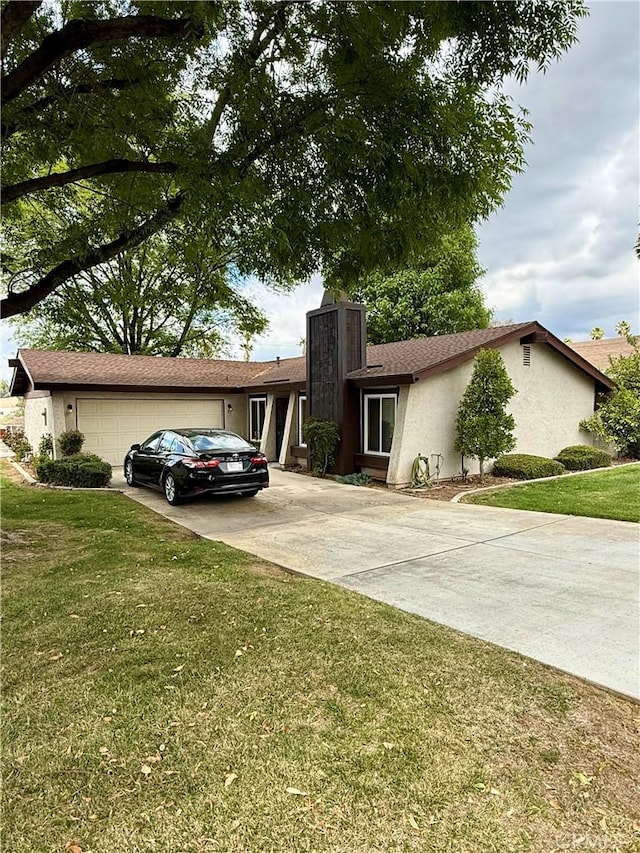 view of front of home with concrete driveway, a chimney, stucco siding, an attached garage, and a front lawn