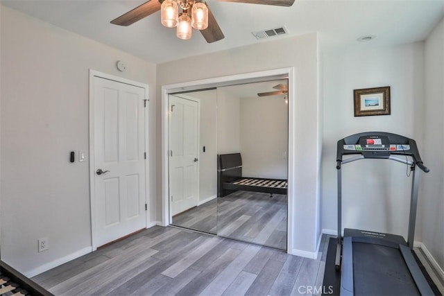 exercise room featuring visible vents, ceiling fan, wood finished floors, and baseboards
