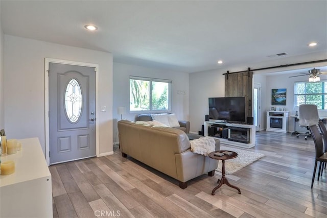 living area featuring visible vents, a barn door, a ceiling fan, light wood-style floors, and recessed lighting