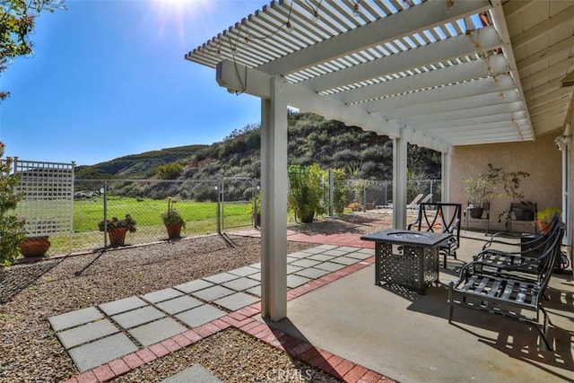 view of patio / terrace featuring a fire pit, a mountain view, fence, and a gate