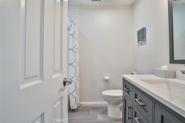 full bath with vanity, baseboards, toilet, visible vents, and wood finished floors