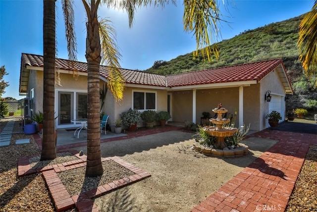 view of front of home featuring a patio area, a tile roof, and stucco siding