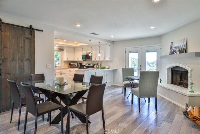 dining room featuring french doors, light wood finished floors, recessed lighting, and a wealth of natural light