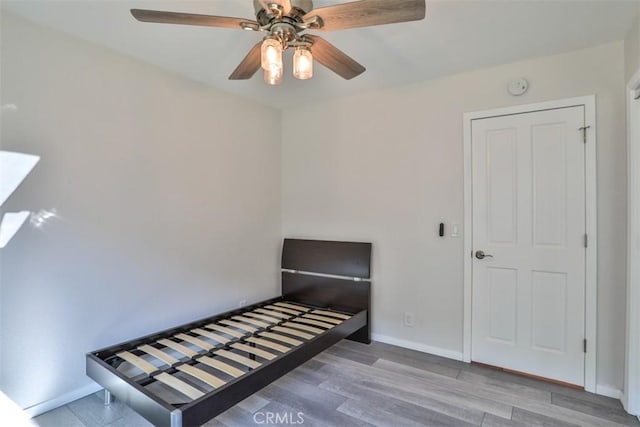 unfurnished bedroom with baseboards, a ceiling fan, and wood finished floors