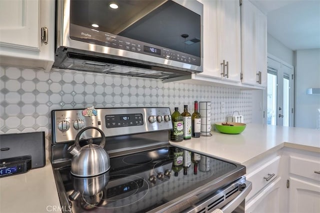 kitchen with stainless steel appliances, tasteful backsplash, white cabinets, and light countertops