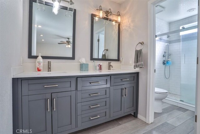 bathroom featuring double vanity, a sink, a stall shower, and wood finished floors