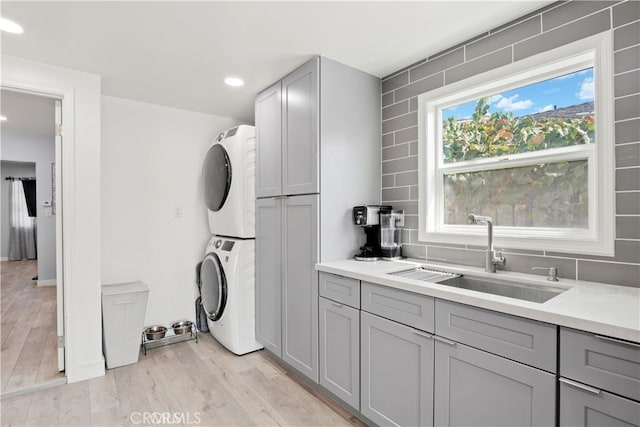 13118 Hoyt St, Pacoima, CA 91331 - washroom with recessed lighting, stacked washing maching and dryer, a sink, light wood-style flooring, and laundry area