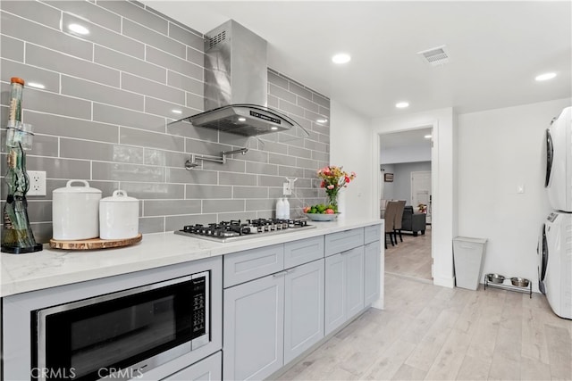 13118 Hoyt St, Pacoima, CA 91331 - kitchen featuring backsplash, stacked washing maching and dryer, appliances with stainless steel finishes, wall chimney range hood, and visible vents