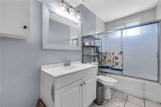 full bathroom featuring toilet, vanity, tile patterned flooring, and bath / shower combo with glass door