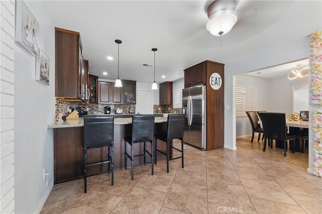 kitchen with dark brown cabinetry, stainless steel appliances, a peninsula, and tasteful backsplash