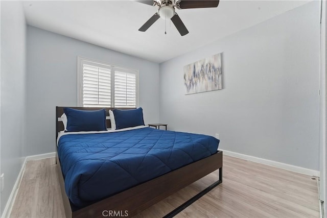 bedroom featuring baseboards, wood finished floors, and a ceiling fan