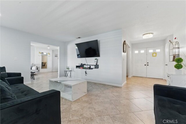 living area with baseboards and light tile patterned floors
