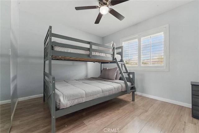 bedroom with a ceiling fan, baseboards, and wood finished floors