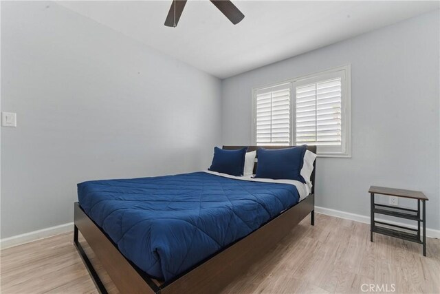 bedroom featuring a ceiling fan, light wood-style flooring, and baseboards