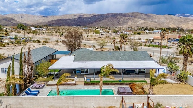 outdoor pool featuring a mountain view, fence, and a patio
