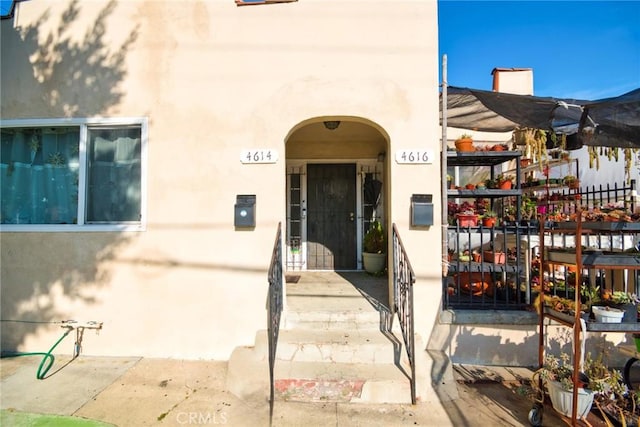 entrance to property with fence and stucco siding
