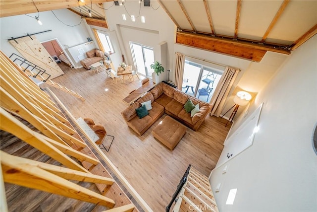 living area featuring wood finished floors, high vaulted ceiling, and beam ceiling