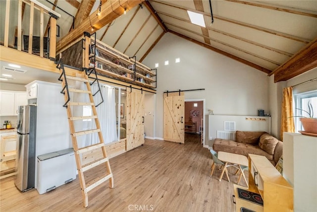 living room featuring visible vents, a barn door, light wood-type flooring, stairs, and high vaulted ceiling
