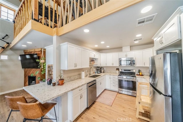 kitchen with light wood-type flooring, appliances with stainless steel finishes, a sink, and visible vents