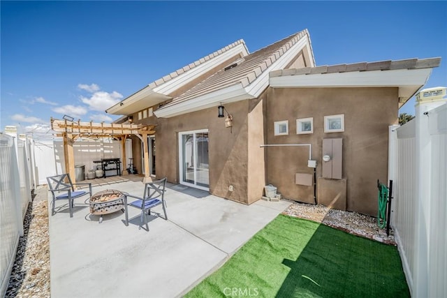 rear view of property featuring a pergola, a fenced backyard, stucco siding, a patio, and a fire pit