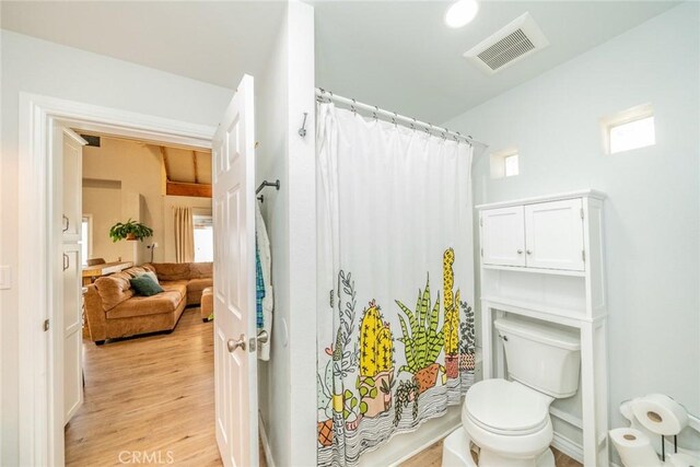 bathroom featuring toilet, wood finished floors, a shower with curtain, and visible vents