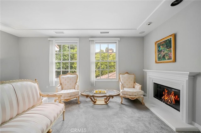 sitting room with a glass covered fireplace, carpet floors, and visible vents