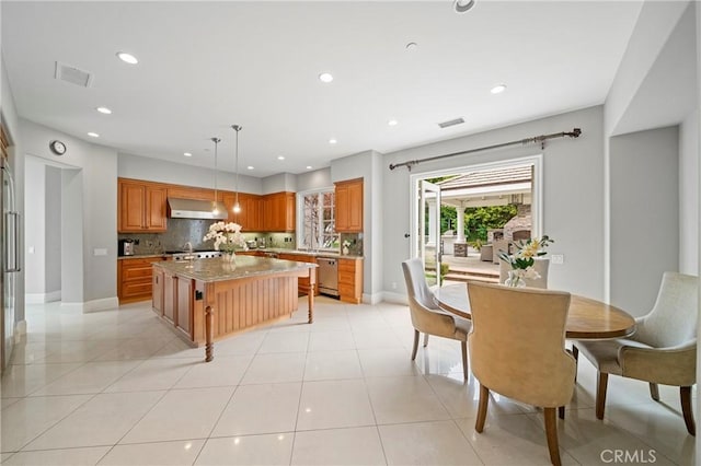kitchen with wall chimney exhaust hood, dishwasher, light tile patterned floors, and a center island