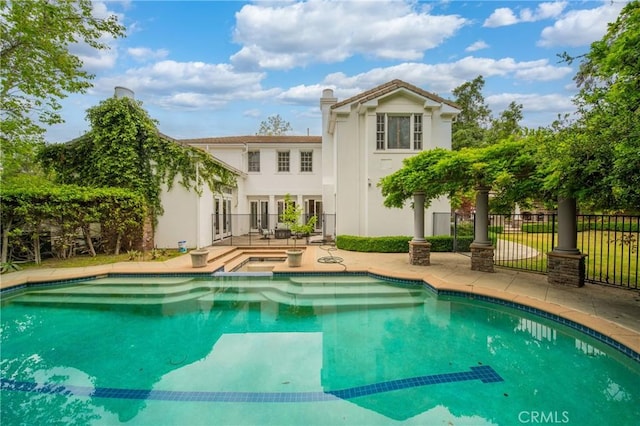 rear view of house with a fenced in pool, a chimney, fence, stucco siding, and a patio