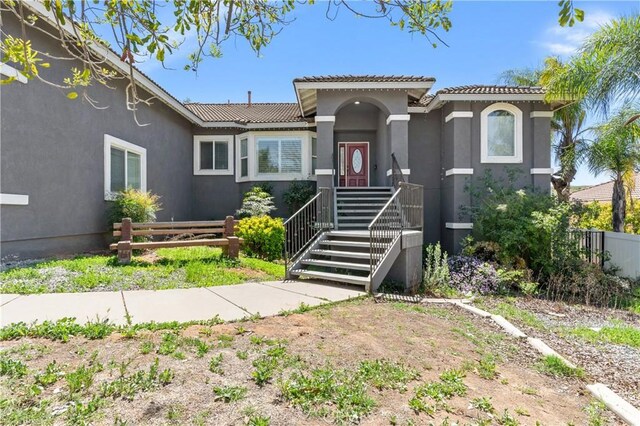 mediterranean / spanish house with stucco siding, fence, and a tile roof