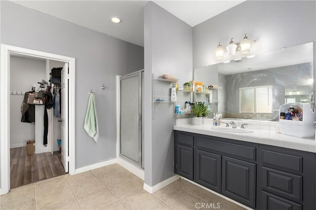 full bathroom with baseboards, a spacious closet, a shower stall, vanity, and tile patterned flooring