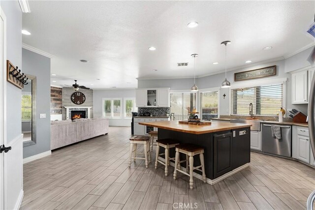 14445 Dove Canyon Dr, Riverside, CA 92503 - kitchen with butcher block countertops, stainless steel dishwasher, a sink, a kitchen bar, and a kitchen island