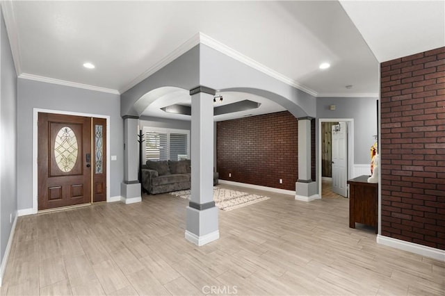 entrance foyer with baseboards, light wood-style floors, arched walkways, and brick wall