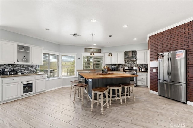 kitchen featuring wall chimney range hood, visible vents, stainless steel appliances, wooden counters, and backsplash