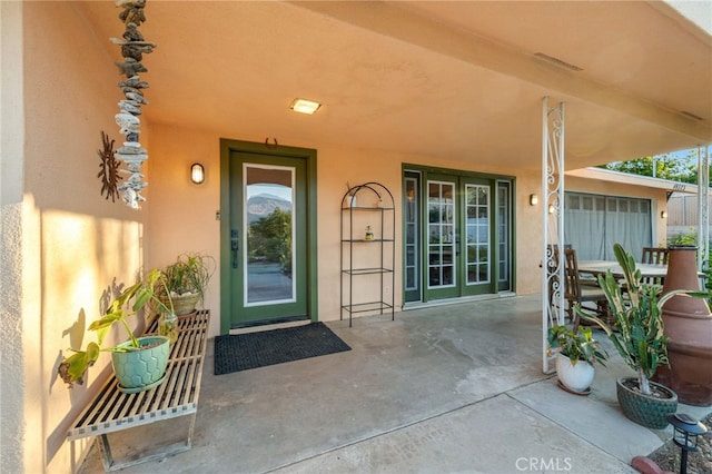doorway to property with outdoor dining area, stucco siding, and a patio