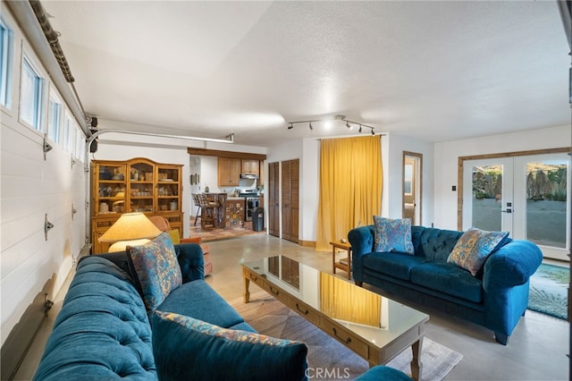 living room with french doors, concrete flooring, track lighting, and a wealth of natural light