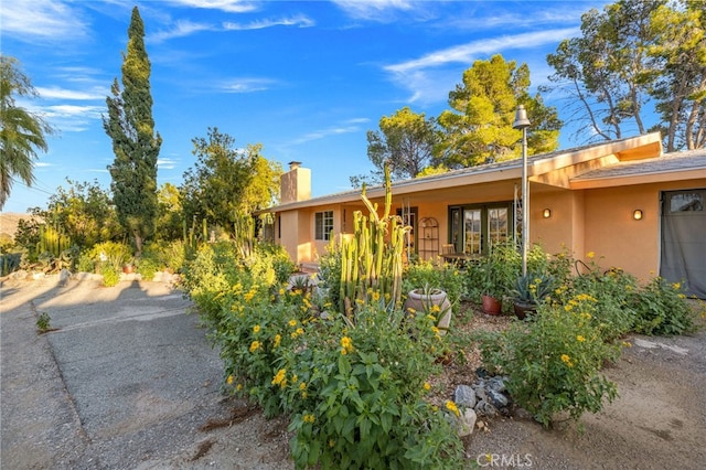 view of front of property featuring a chimney and stucco siding