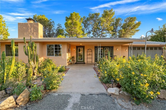 view of front of home with stucco siding and a chimney