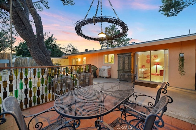 deck at dusk with fence, outdoor dining area, area for grilling, and a patio area