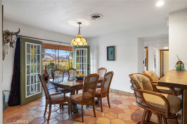 dining area with baseboards, a textured ceiling, and visible vents
