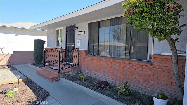 view of exterior entry featuring brick siding and stucco siding
