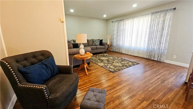 living area with baseboards, wood finished floors, and recessed lighting