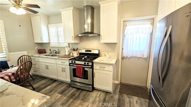 kitchen featuring plenty of natural light, wall chimney range hood, stainless steel appliances, and a sink