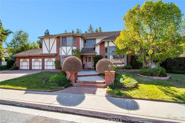 29528 Ridgeway Dr, Agoura Hills, CA 91301 - tudor-style house featuring driveway, a front lawn, stucco siding, and an attached garage