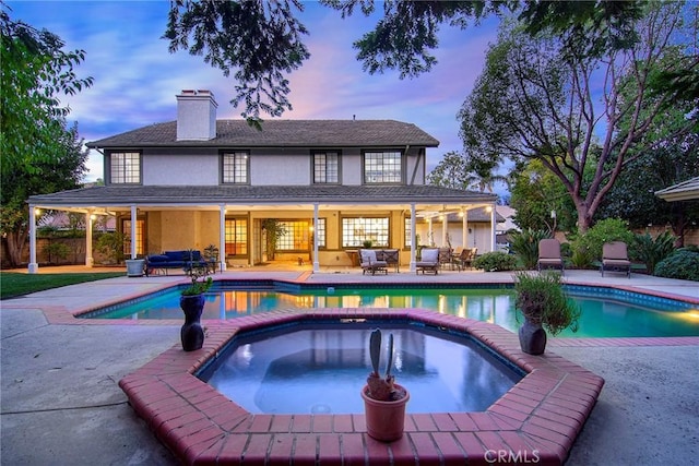 29528 Ridgeway Dr, Agoura Hills, CA 91301 - pool at dusk featuring a patio, a pool with connected hot tub, and an outdoor living space