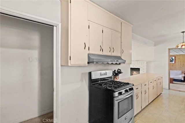 kitchen featuring decorative light fixtures, under cabinet range hood, gas stove, and light countertops